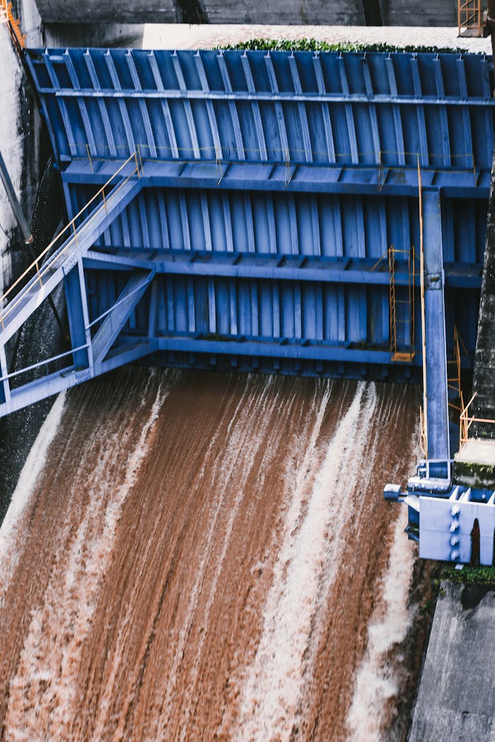 High-angle view of a blue industrial dam gate controlling water flow.