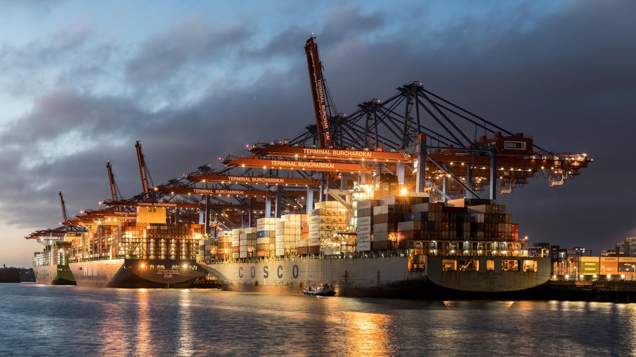 Illuminated cargo ships at Terminal Burchardkai, Hamburg port in the evening.