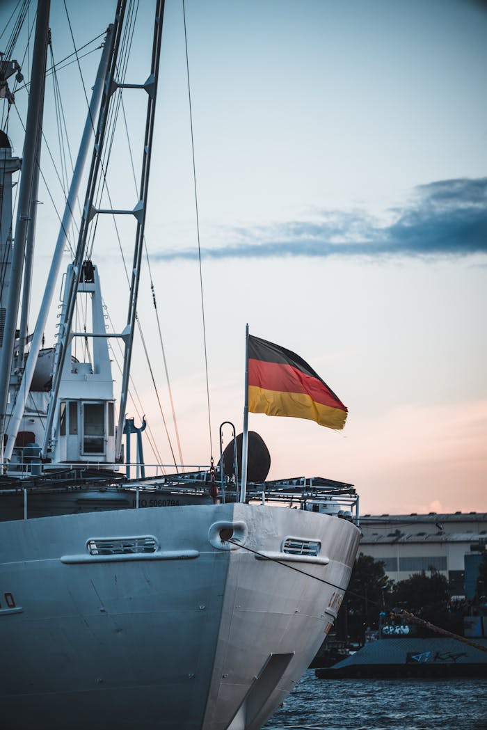 Ship with German flag docked at harbor during sunset, showcasing nautical and travel themes.